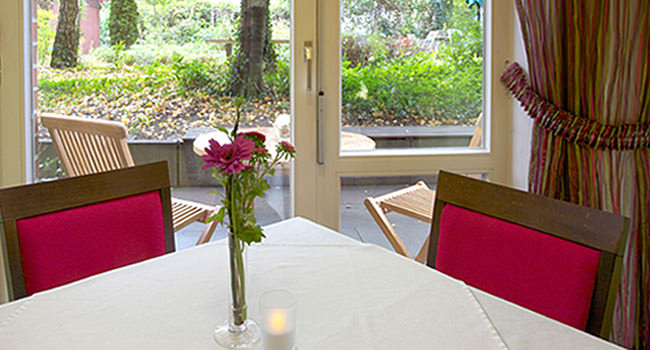 Frühstückstisch: Rote Stühle, Kerze und Blick in den Garten